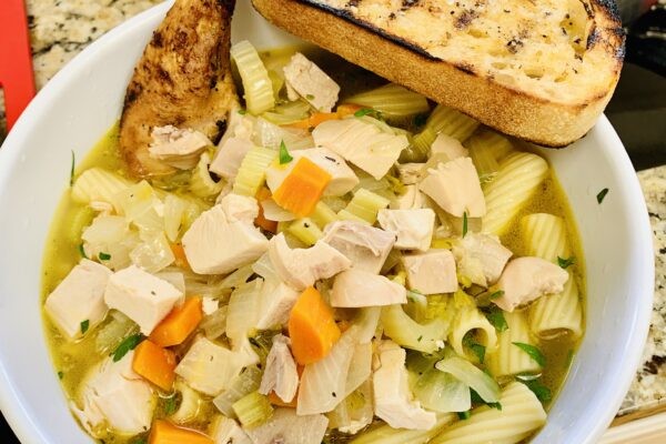Chicken noodle soup with a braised drumstick and grilled sourdough bread.