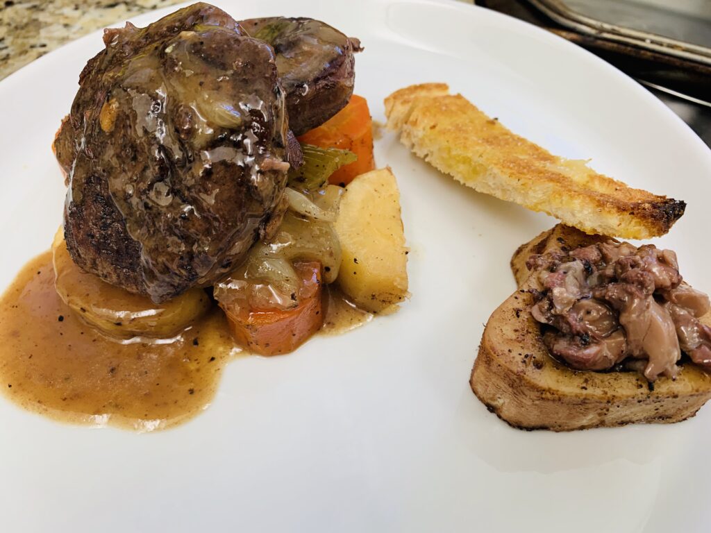 Beef cheek pot roast with root vegetables and bone marrow crouton prepared using classic slow-cooking techniques