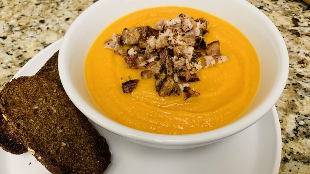Creamy butternut squash soup topped with crispy bacon and served with toast