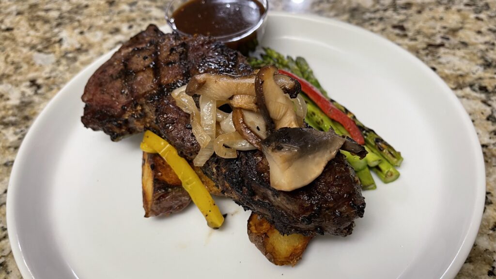 Grilled steak plated with mushrooms, asparagus, grilled vegetables, and restaurant-style presentation