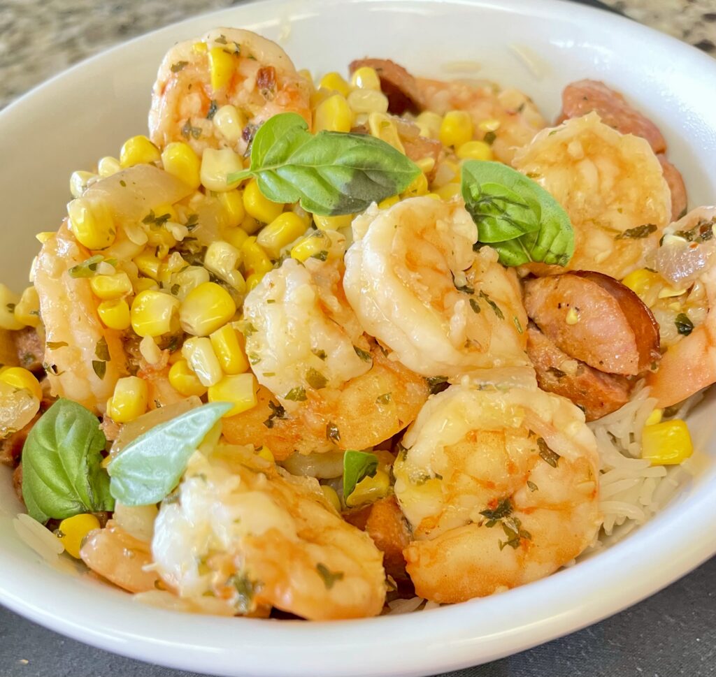 Garlic Herb Shrimp and Andouille Sausage Rice Bowl served with sweet corn, basmati rice, garlic herb butter, and fresh basil.