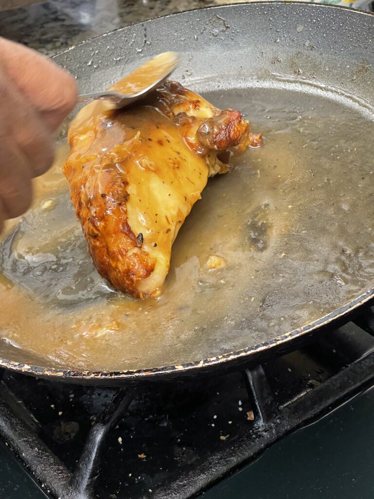 Chef Wendell White basting roasted chicken breast with pan sauce reduction in a skillet